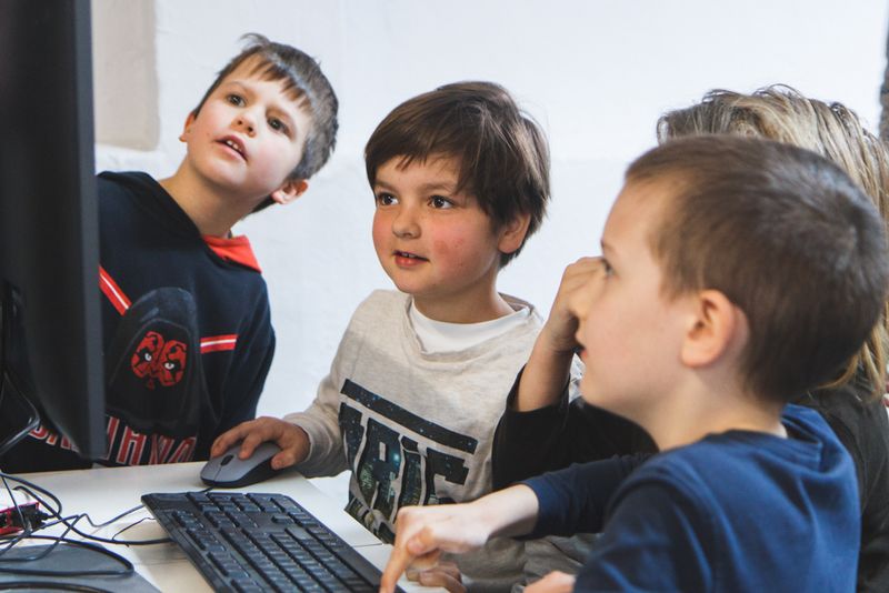 Vier Kinder starren gebannt auf ihre eigene Minecraft-Programmierung am Raspberry Pi
